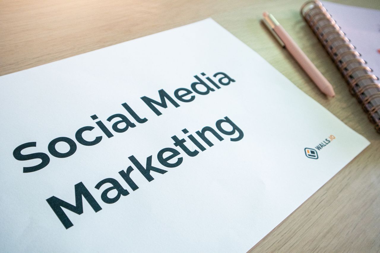 services-06 A close-up view of a social media marketing document laid out on a desk, alongside a pen and notebook.